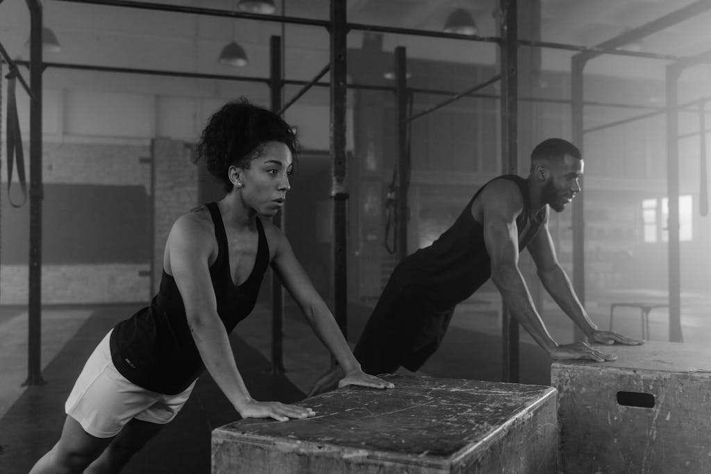 A man and woman doing inclined push-ups in a gym. Black and white photo.